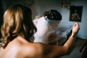 Hochzeitsfotografin Köln hält zart den Schleier der Braut bei der Vorbereitung im hellen Zimmer.