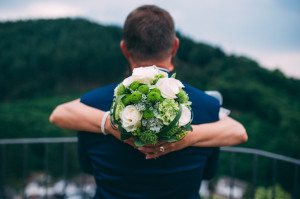 Braut und Bräutigam umarmen sich still im Wald, den Blumenstrauß in der Hand – Hochzeitsreportage NRW.