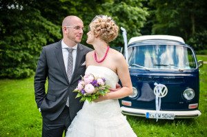 Brautpaar lächelt sich liebevoll an vor blauem VW-Bus – Hochzeitsfotografin Köln Reportage.