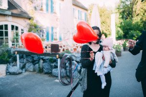 Eine Mutter mit Baby bei einer Hochzeit Gut Knittkuhle Düsseldorf, rote Herzballons im Vordergrund.