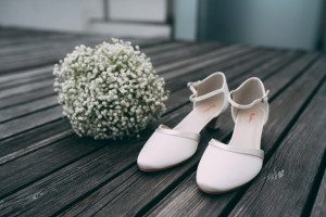 Elegante Brautschuhe und Schleierkraut-Bouquet auf Holz – Hochzeitsfotografin Köln Moment.