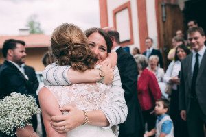 Zwei Frauen lachen umarmt auf einer Hochzeit in Köln, eine hält einen Brautstrauß – Hochzeitsreportage NRW.