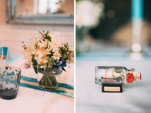 Detail der Hochzeitstischdekoration: weiße und gelbe Blumen, Flaschenpost „Anik & Claude“ – Hochzeitsfotografin Köln.