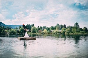 Brautpaar mit roten Ballons auf Holzfloß, ruhiger See – Hochzeitsfotografin Köln, natürliche Momente.