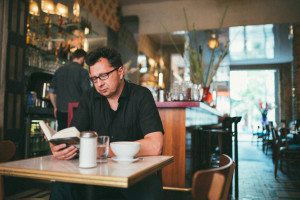 Mann genießt ruhige Momente mit einem Buch in einem Kölner Café, Tageslicht und gemütliche Atmosphäre.