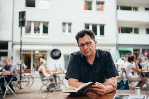 Ein Mann genießt einen ruhigen Moment beim Lesen in einem Café – authentische Straßenszene, Hochzeitsreportage NRW.