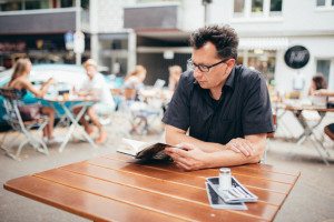 Ein Mann mit Brille liest entspannt im Straßencafé – Hochzeitsreportage NRW Alltagsszene.