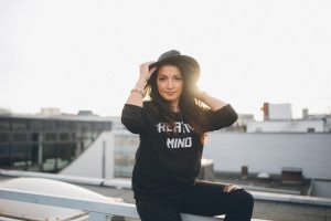 Lächelnde Frau mit schwarzer Hut auf einem Kölner Dach – natürliche Outdoor-Portraits von Hochzeitsfotografin Köln.
