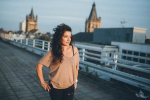 Braut mit langen Locken genießt den Sonnenuntergang auf einem Kölner Dach – Hochzeitsfotografin Köln.