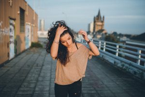 Frau mit langen dunklen Haaren auf einem Kölner Dach, entspannt beim Portraitshooting mit Blick zum Dom.