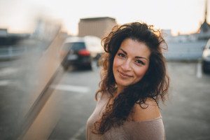 Lächelnde Frau mit lockigem Haar bei Sonnenuntergang, entspannte Momentaufnahme – Hochzeitsfotografin Köln.