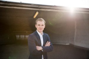 Ein Bräutigam im Anzug lächelt sanft in die Kamera, Sonnenlicht im Hintergrund – Hochzeitsfotografin Köln.