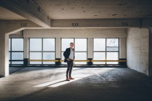 Person im Business-Outfit steht entspannt im Sonnenlicht im Parkhaus – moderne Bewerbungsfotos Köln.