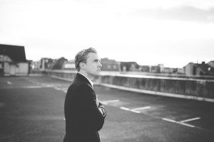 Ein Bräutigam im Anzug steht entspannt auf einem Parkdeck – Hochzeitsfotografin Köln, echte Momente.