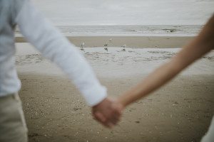Ein Paar hält Händchen am Nordseestrand bei Noordwjik, Moment festgehalten von Hochzeitsfotografin Köln.
