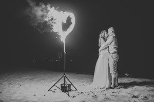 Paar umarmt sich am Strand bei Nacht, Herz aus Feuer daneben – Hochzeitsreportage NRW.