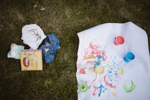 Im Gras verstreute Kinderkunst und Kleidung – authentische Familienfotos der Hochzeitsfotografin Köln.