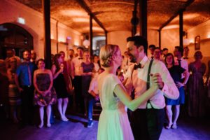 Brautpaar tanzt lachend beim Hochzeitstanz, Gäste schauen liebevoll zu – Hochzeitsreportage NRW.