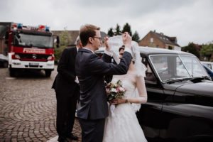 Der Bräutigam hebt den Schleier der Braut vor dem Standesamt in Bonn, festgehalten von Hochzeitsfotografin NRW.