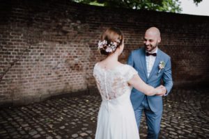 Brautpaar lächelt sich Hand in Hand auf Kopfsteinpflaster an – Hochzeitsfotografin Köln hält echte Momente fest.
