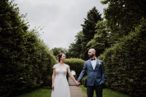 Braut und Bräutigam halten sich an der Hand im Garten – natürliche Hochzeitsfotografie Köln.