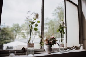 Sonnenlicht fällt auf bunte Blumenvasen am Fenster – detailverliebte Hochzeitsreportage NRW.
