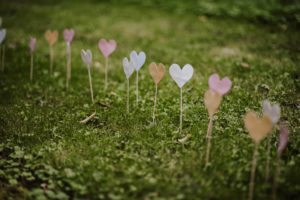 Handgefertigte Papierherzen auf Stäben säumen einen Garten in NRW – schlichte, herzliche Hochzeitsmomente.