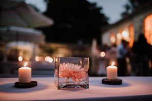 Rosa Blume in einer Glasvase, daneben glühen Kerzen – Ausschnitt aus einer entspannten Hochzeitsreportage NRW.