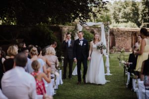 Brautpaar lächelt Hand in Hand beim Auszug nach standesamtlicher Trauung Schloss Föhren.