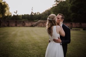 Brautpaar umarmt sich und küsst sich herzlich im Grünen bei ihrer Hochzeit auf Schloss Föhren, Hochzeitsfotografin Köln.