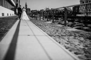 Brautpaar an der Kölner Rheinpromenade beim Spaziergang, festgehalten von Hochzeitsfotografin Köln.
