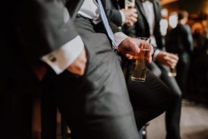 Freunde im Anzug stoßen an der Bar an – entspannte Hochzeitsreportage NRW Momentaufnahme.