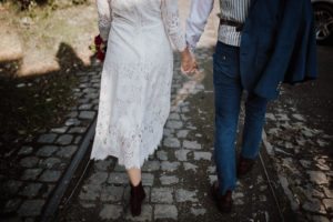 Paar hält Händchen auf Kopfsteinpflaster – echte Hochzeitsmomente von Hochzeitsfotografin Köln.