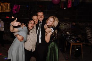 Vier Freunde lachen gemeinsam auf der Tanzfläche – natürliche Hochzeitsreportage NRW.