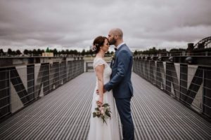 Ein zärtlicher Stirnkuss auf einer Metallbrücke – natürliche Hochzeitsfotografie Bonn, echte Emotionen.
