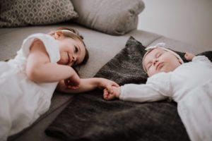 Kleines Mädchen hält die Hand eines schlafenden Babys – liebevolle Hochzeitsreportage NRW.