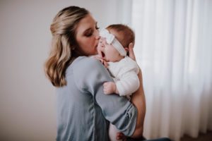 Mama hält ihr gähnendes Baby liebevoll im Arm – natürliche Momentaufnahme Hochzeitsreportage NRW.