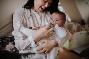 Eine Mutter beruhigt ihr Baby am Kinderbett, zartes Licht im Stil einer Hochzeitsreportage NRW.