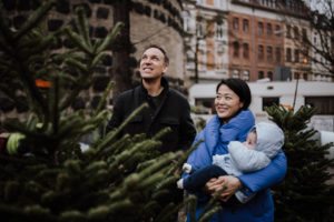 Junges Paar mit Baby genießt einen liebevollen Moment im Grünen – Hochzeitsfotografin Köln.