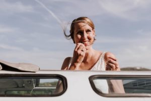 Braut lächelt durch das offene Autofenster beim Auszug – Hochzeitsreportage NRW mit Herz.
