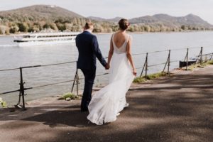 Brautpaar spaziert Hand in Hand am Rhein – echte Hochzeitsmomente von Hochzeitsfotografin Köln.