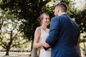 Brautpaar hält sich an der Hand, lächelt vertraut im Sonnenlicht – Hochzeitsfotografin Köln.