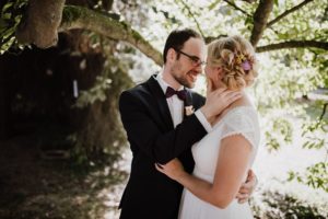 Hochzeitspaar lächelt sich unter Bäumen an – natürliche Hochzeitsreportage NRW.