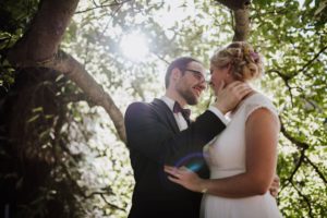 Brautpaar lehnte sich vertraut aneinander unter Bäumen, festgehalten von Hochzeitsfotografin Köln.