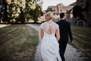Brautpaar spaziert Hand in Hand über einen Kiesweg – natürliche Hochzeitsfotografie Bonn.