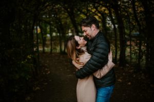 Ein Paar umarmt sich lachend auf einem Baumweg – natürliche Hochzeitsfotografie Bonn.