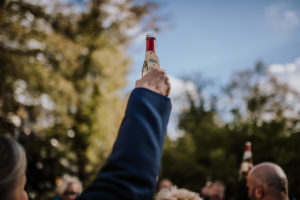 Freunde feiern draußen in der Sonne, ein Toast unter Bäumen – natürliche Hochzeitsfotografie Bonn.