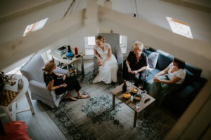 Vier Freundinnen lachen und plaudern entspannt im Wohnzimmer, natürliche Hochzeitsfotografie Köln.