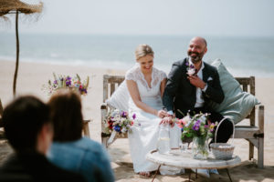 Brautpaar hält sich an der standesamtlichen Trauung am Strand lächelnd an den Händen – Hochzeitsfotografin Köln.