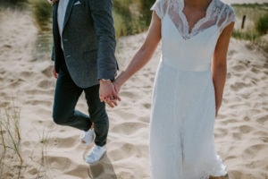Brautpaar Hand in Hand auf sandigem Weg – natürliche Hochzeitsfotografie Bonn, echt und ungestellt.
